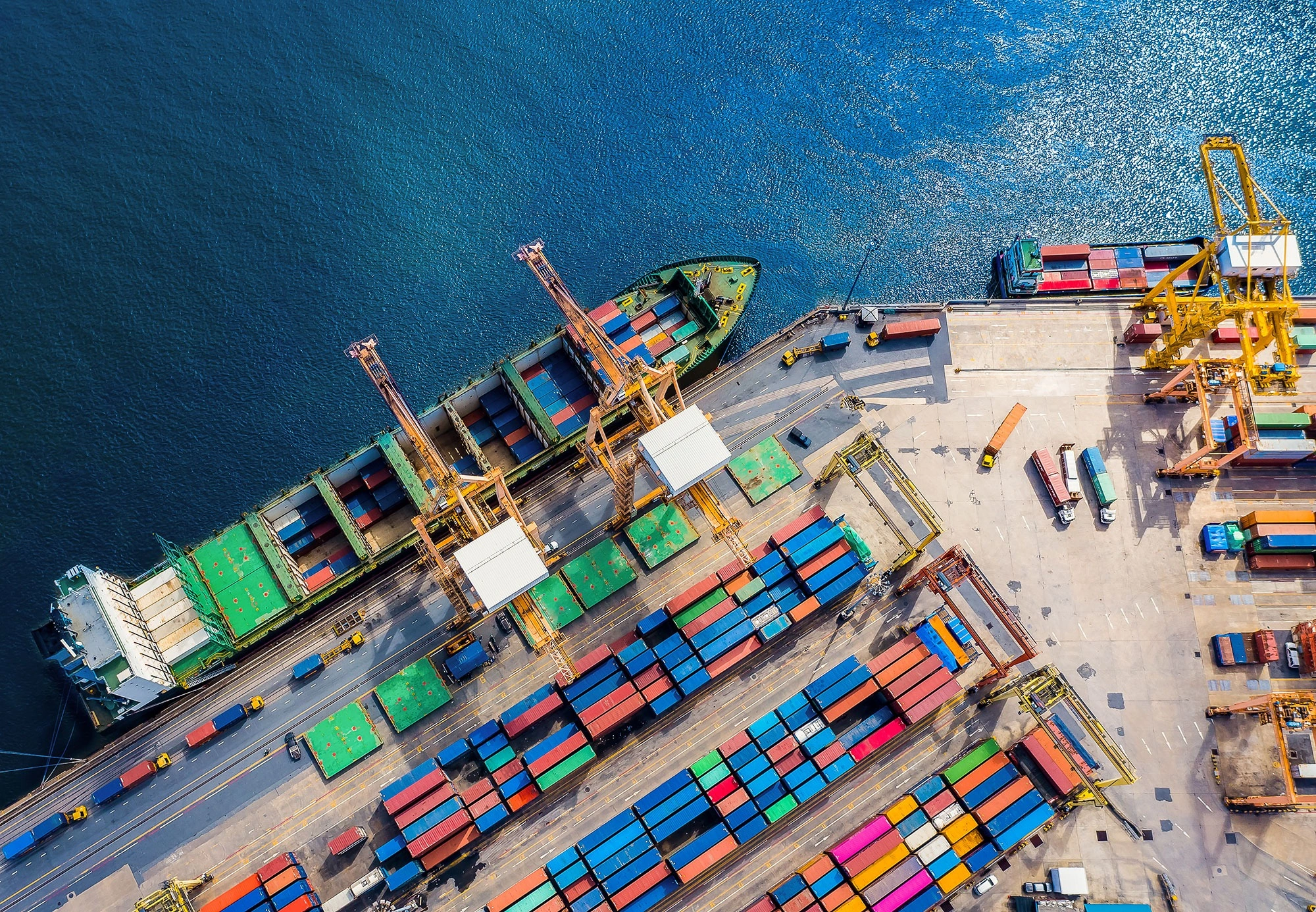 Container Ship Operations at an International Cargo Port Aerial view of a container ship being loaded and unloaded by cranes at a busy international cargo port.