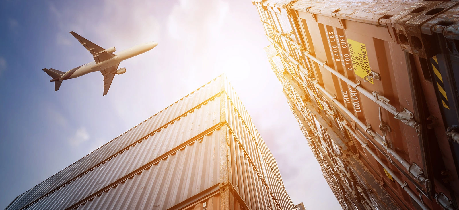International Air Freight and Container Logistics Cargo airplane flying above stacked shipping containers, representing international air freight and global logistics.