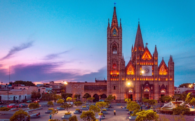 Illuminated Guadalajara Cathedral overlooking a public plaza at dusk in Guadalajara, Mexico.